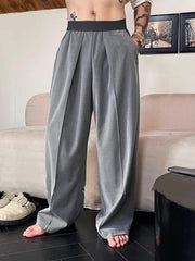 Pantalon ample uni à plis gris — vue portée de face, dans un salon