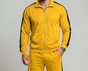 Ensemble de sport zippé — jaune à bandes noires, buste de face, main dans la poche