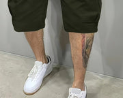 Short à poches biaisées — gros plan du bas du short vert militaire avec baskets blanches