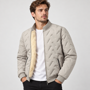 Blouson beige grisé à col montant porté ouvert, avec relief géométrique et intérieur clair.