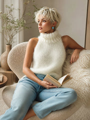 Haut blanc col roulé — vue portée assise dans un fauteuil blanc, livre à la main