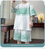 T-shirt à motif lettre — blanc porté de face avec short imprimé, lunettes en main