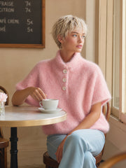 Pull rose boutonné col montant — vue portée assise à une table de café, tasse blanche