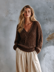 Pull brun grosse maille sequins — vue portée en pied, devant un fond texturé