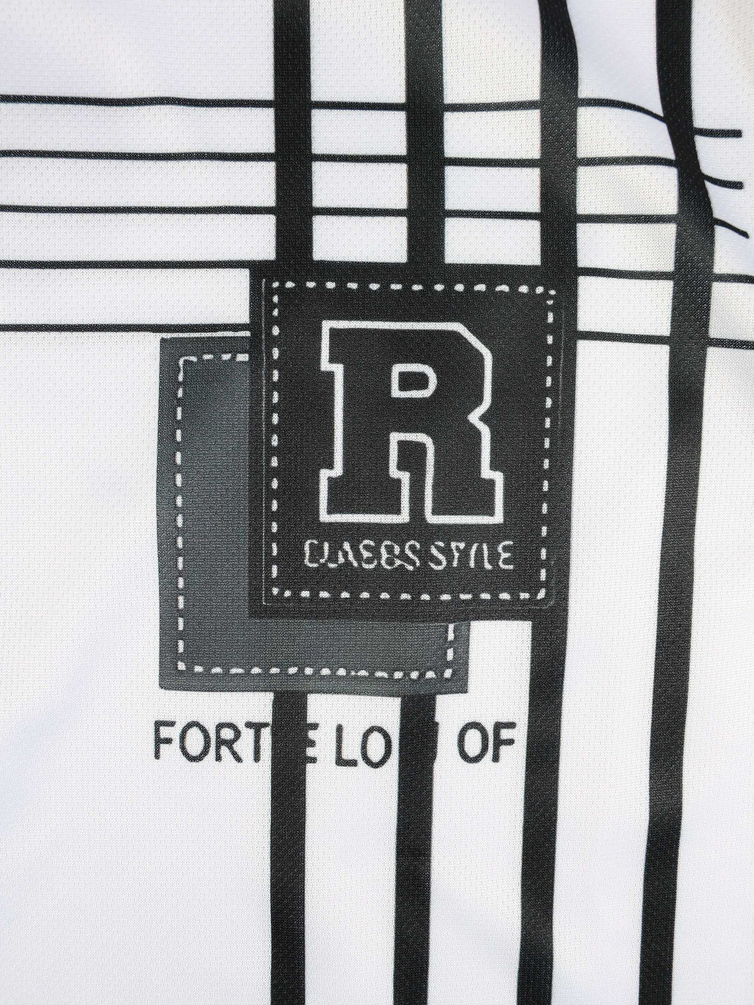 Gros plan d’un t-shirt blanc à motifs noirs avec lettre « R » et texte « CLASSIC STYLE » visible.