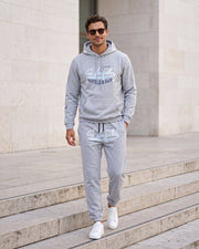 Ensemble sweat et jogging gris clair — vue portée en marche, escaliers en pierre