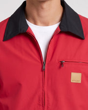 Veste courte zippée rouge, gros plan du col et de l'écusson à inscription