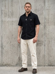 Surchemise en denim d’esprit rétro noir — vue portée en pied, avec pantalon crème
