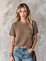Pull brun à poche poitrine — vue portée en pied, devant un mur gris