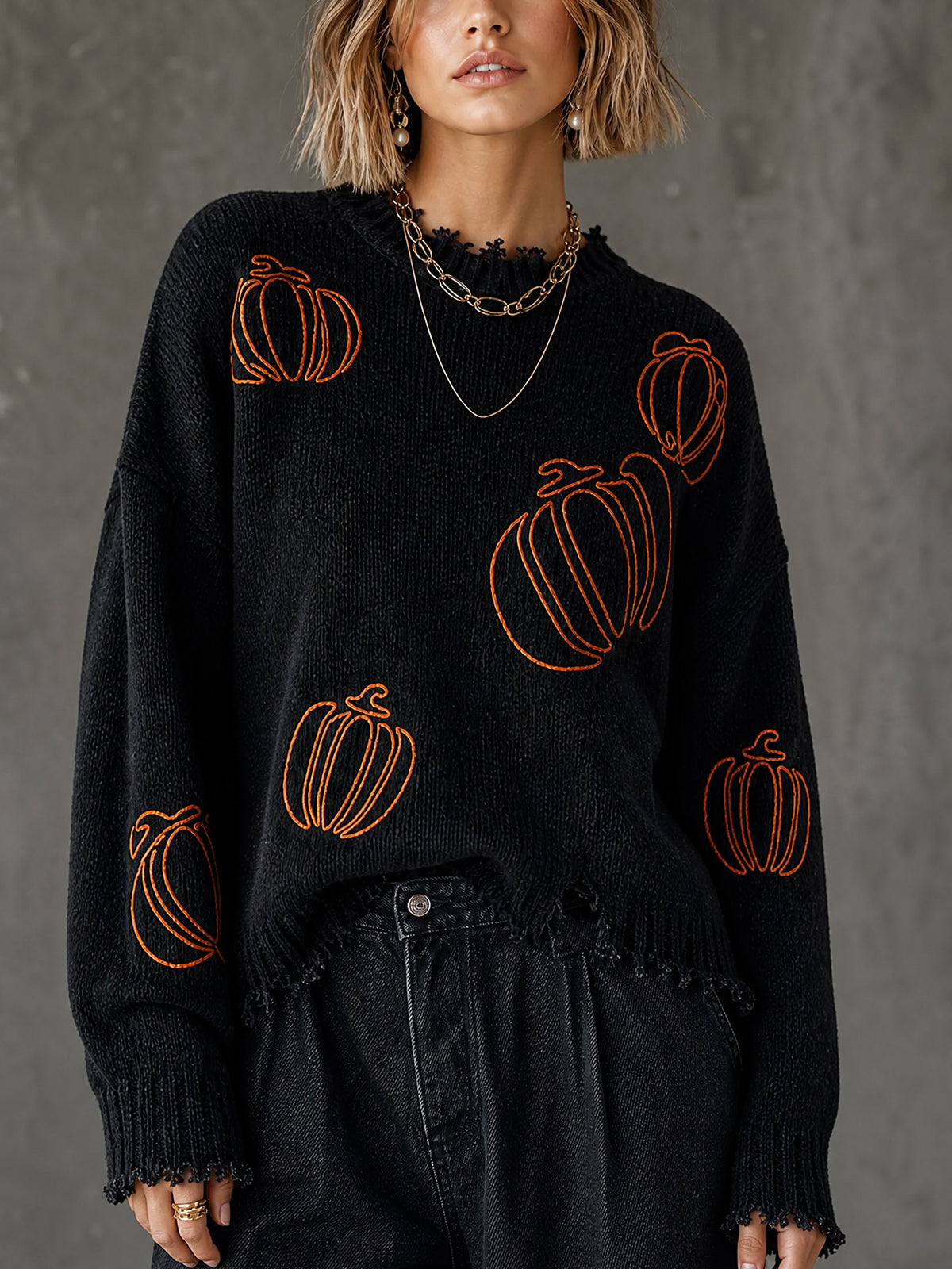 Pull noir à citrouille brodée — vue portée de face, citrouilles orange sur le devant, pantalon noir