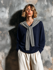Pull marine gris effet foulard — vue portée en pied, devant un mur texturé