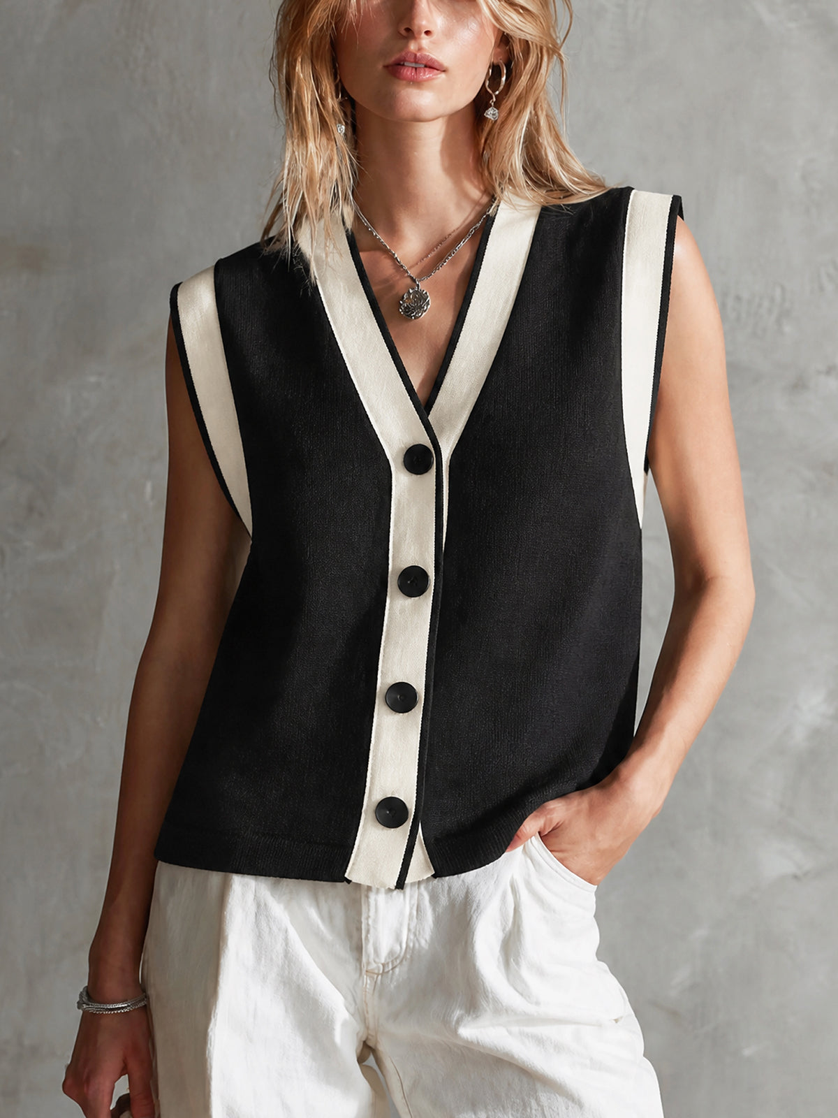 Gilet noir crème col V — vue portée de face, boutons foncés et bordure claire, pantalon blanc