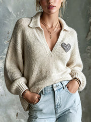 Pull beige écusson cœur — vue portée de face, cadrée à la taille