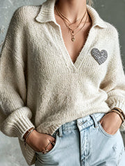 Pull beige écusson cœur — gros plan de l'encolure en V, du col et de l'écusson en forme de cœur