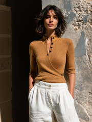 Pull camel croisé col montant — vue portée de face, plan plus large, architecture en pierre