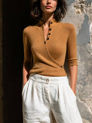 Pull camel croisé col montant — vue portée de face, pantalon blanc, embrasure de porte lumineuse