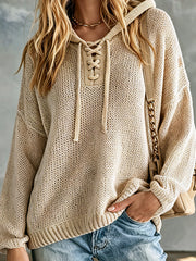 Pull beige capuche col lacé — gros plan du col lacé, des œillets métalliques et des cordons à pompons