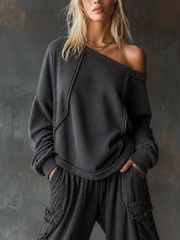 Sweat anthracite à encolure dégagée — vue portée de face, épaule dégagée, mains dans les poches du jogging