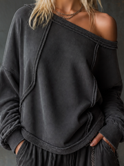 Sweat anthracite à encolure dégagée — gros plan de l'encolure asymétrique et des coutures apparentes