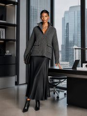 Ensemble pull gris jupe noire — vue portée adossée à un bureau dans un bureau lumineux