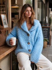 Cardigan bleu à col châle — vue portée assise au comptoir en bois, tasse blanche, pantalon blanc