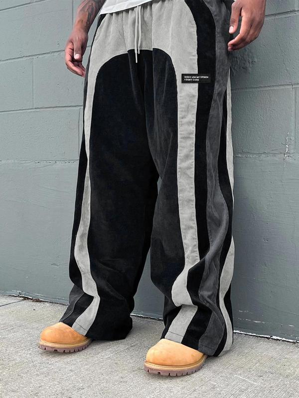 Pantalon ample à panneaux contrastants noir et gris — vue portée de trois-quarts, devant un mur gris