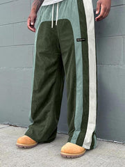 Pantalon ample à panneaux contrastants vert — vue portée de trois-quarts, devant un mur gris