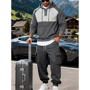 Ensemble sweat à capuche gris foncé — vue portée de face, valise à la main