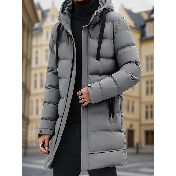 Veste grise matelassée à capuche, portée de face.