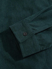 Détail du poignet boutonné et de la texture côtelée vert foncé.