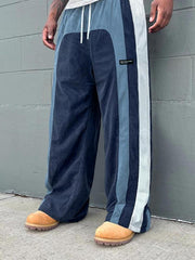 Pantalon ample à panneaux contrastants bleu — vue portée de trois-quarts, devant un mur gris