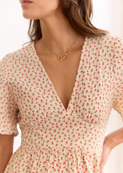 Détail du décolleté en V et des fronces de la robe beige à petites fleurs rouges.