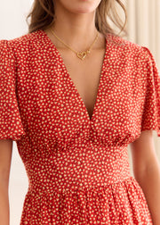 Détail du décolleté en V et des fronces de la robe rouge à petits motifs clairs.
