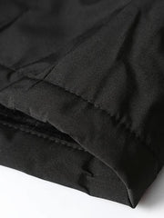 Gros plan sur une surpiqûre au bord du tissu sombre de la veste.