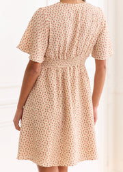 Robe courte beige à fleurs rouges vue de dos, avec taille smockée et manches courtes.