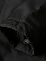 Détail d’une couture du tissu sombre, avec la doublure noire à proximité.