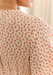 Détail des petites fleurs rouges et de l’épaule au dos de la robe beige.
