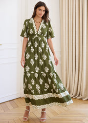 Robe longue kaki à motifs floraux écrus, portée de face avec la jupe en mouvement.