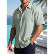 Chemise d'été à manches courtes vert sauge — vue portée de profil, plan buste, devant une piscine
