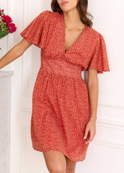 Robe rouge à petits motifs clairs, portée de face dans une pose inclinée.