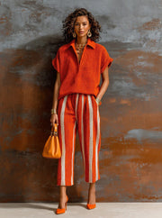 Ensemble maille orange et blanc — vue portée en pied, sac à main orange, mur texturé marron