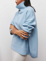 Pull oversize col roulé bleu ciel — vue portée de profil, bras croisés