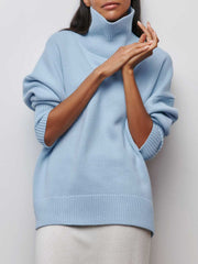 Pull oversize col roulé bleu ciel — vue portée de face, mains près du visage