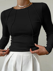 Top manches longues passepoilé noir — vue portée de face, cadrée à la taille, pantalon blanc