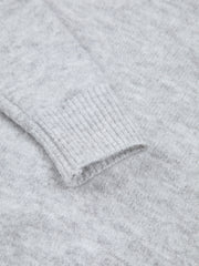 Pull asymétrique épaule dénudée gris clair — gros plan sur le poignet côtelé