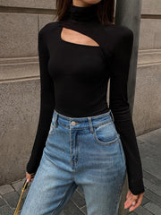 Top asymétrique découpe col montant noir — vue portée de face, cadrée à la taille, jean bleu