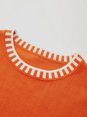 Top tricot bordure contrastée orange — gros plan sur l'encolure et la bordure blanche ondulée