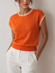 Top tricot bordure contrastée orange — vue portée de face, rentré dans un pantalon blanc