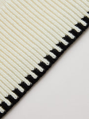 Ensemble pull jupe bordure contrastée crème — gros plan sur le bord plissé et la bande noire