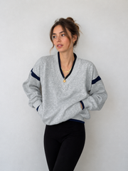 Sweat oversize finitions contrastées gris clair — vue portée de face, cadrée à la taille, col en V rayé bleu marine
